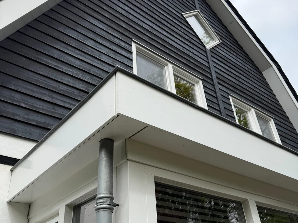 Schone houten gevel, witte kozijnen en dakrand van een woning