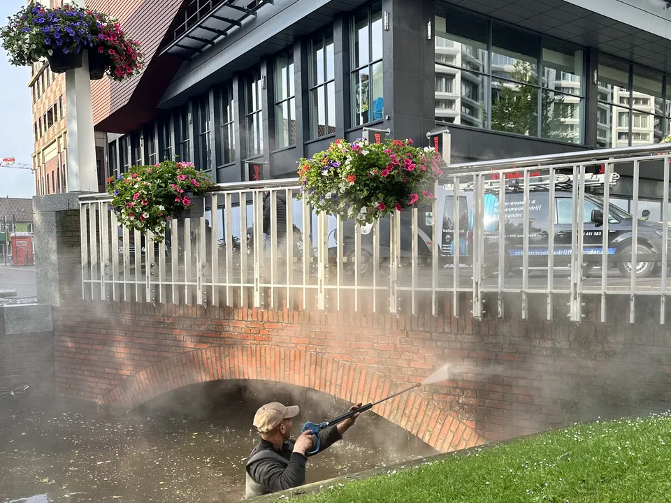Medewerker reinigt een bakstenen brug met de hogedrukspuit