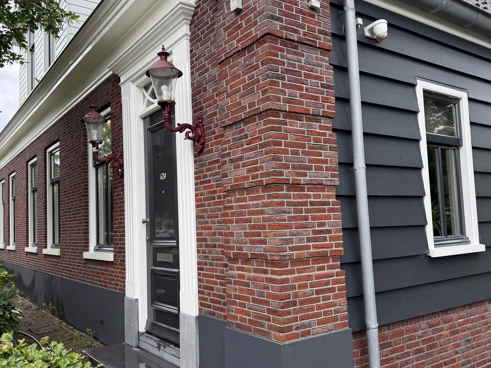 Gereinigde bakstenen gevel met houten beschieting en entree