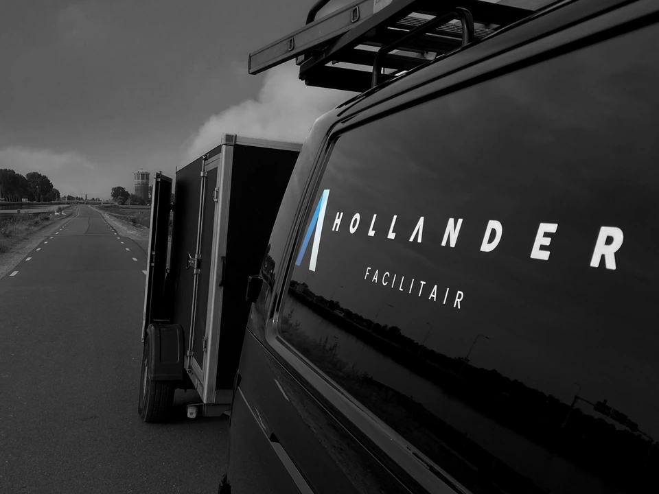 Bedrijfsbus met aanhanger van Hollander Facilitair onderweg langs de Zaan